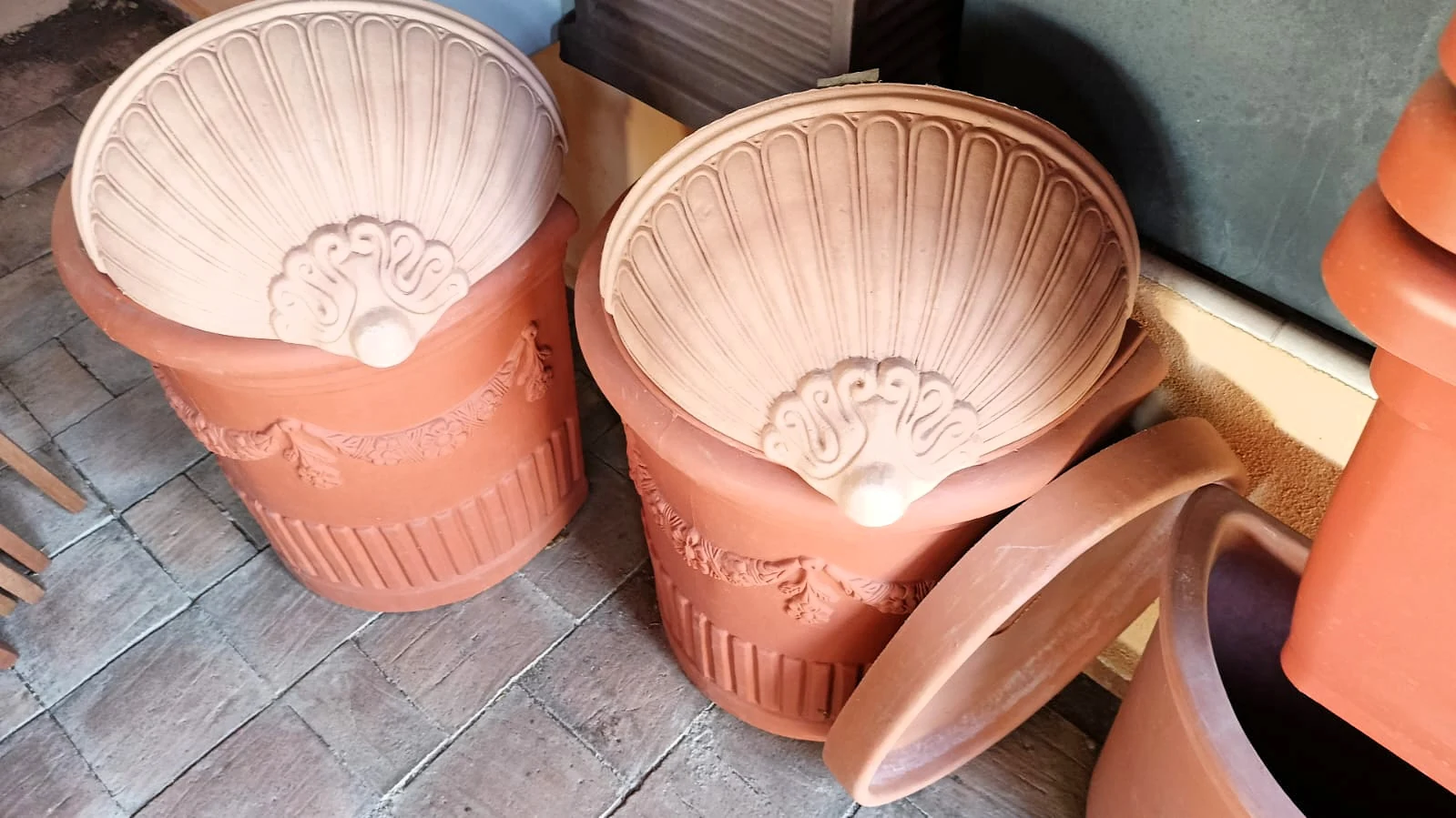 Due vasi a conchiglia in terracotta con i festoni, esposti in negozio